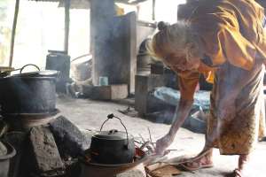 Mbah Warno "Anderson" sedang memasak nasi secara tradisional